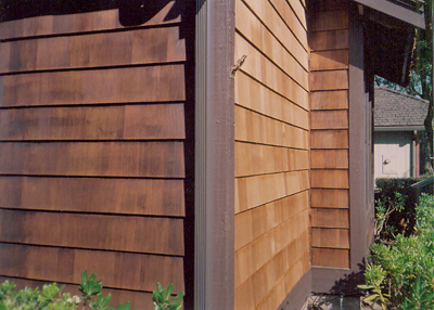 Shingle siding in-process close up. Near face: power-washed and stained/perpendicular face: shingle panels replaced, not yet stained/Far face: shingle panels, power-washed only